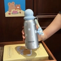 Detail of silver polka dot insulated bottle with a light blue spherical cap and floral charm - Blue Polka Dot