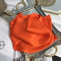 Detailed close-up of a vibrant orange 100% mulberry silk scarf folded into a floral shape - 15x150cm / Orange