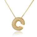 Macro shot of gold letter C pendant with micro-pave cubic zirconia on thin chain - Letter C