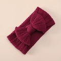 Detailed view of dark pink knitted bow headband with fine jacquard texture on beige surface - Burgundy