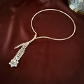 Macro shot of gold tassel necklace with marquise zircons on deep red satin fabric - Gold Zircon Wheat Ear Necklace