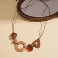 Dettaglio di collana boho con anelli in rattan intrecciato, elementi in legno e perline - Stile Geometrico in Legno di Rattan / Collana-Caffè