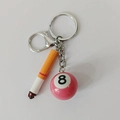 Detailansicht von Zigaretten- und pinkfarbenem Poolbillard-Anhänger an einem Schlüsselanhänger - Kurze Zigarette mit Rosa Poolkugel