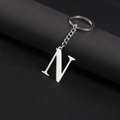 Polished silver stainless steel letter N keychain pendant on a dark leather background - Letter N