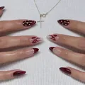 Detailed view of burgundy almond nails with white dots and red ribbon art on fabric - Bz1654 Purple Butterfly Spot / Glue Type
