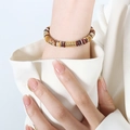 Bracciale etnico con perline a disco marroni, beige e dorate indossato al polso - Braccialetto (E426)