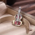 Detailed close-up of a luxury violin brooch with red rhinestones in a beige jewelry box - Silver Base Pink Rhinestone
