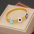 Detail eines goldenen Evil Eye Armbands mit blauer Emaillierung auf einer Box - Dreifacher Teufelsauge Stil(3#)