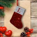 Macro detail of red sequin Christmas stocking with letter L embroidery and festive decor - L