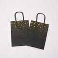 Elegant black kraft paper gift bag featuring gold foil stars and twisted rope handles - Black Card Single-Sided Bronzing Star Dots