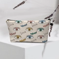 Detail of canvas evil eye makeup bag with Look text on a white geometric stand - 09-Beige Look Text