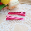Close-up of pink gradient metal hair clips with wavy texture on white lace background - Rose Red