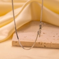 Close-up of silver snake chain necklace with delicate bow pendant on satin background - Bowknot Necklace / Steel