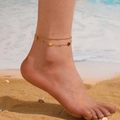 Dubbellaagse gouden enkelband met klavertjes en diamantjes op een zonnig strand - Enkelbandje (Q501) / Goud