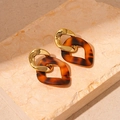 Detail von Schildpatt-Resin-Ohrringen mit polierten Goldringen auf beigem Steinuntergrund - 925 Silberstecker / Braunes Geometrisches Gehänge