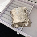 Detailed macro of wide silver cuff with intricate floral and paisley engraving - Silver-Pattern