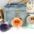 Dettaglio del portachiavi mostro di peluche con chiusura dorata su una borsa di jeans - confezione in singolo sacchetto opp / arancio-rosso