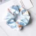 Close-up of blue and orange tie-dye satin scrunchies with soft silk texture on marble - Tie-Dye Blue