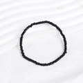 Close-up of black beaded bracelet with polished round beads on white textured background - Black