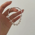 Details von Barock-Süßwasserperle und unregelmäßigem Silberarmband an einer Hand - Unregelmäßiges Zweigdesign / Silber