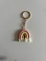 Detail of handmade rainbow keychain with colorful woven rope and white cotton tassels - Pink Yellow