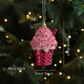 Pink glitter cupcake Christmas ornament hanging on a festive tree with warm lights - Ice Cream Charm