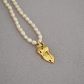 Macro shot of freshwater pearl necklace with an artistic golden body pendant - Body Silhouette