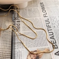 Detailed view of elegant gold square snake chain necklace on a vintage paper background - Gold