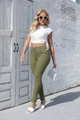 Outdoor shot of women's olive green high-waisted skinny jeans with button fly detail - S / Green