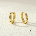 Dettaglio macro di orecchini a cerchio dorati con pietre di zircone viola - Zircone Viola / Viola