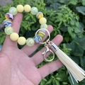 Macro detail of silicone beads keychain bracelet with yellow beads and cream tassel - Yellow