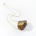 Detailed close-up of a large raw brown tiger eye stone pendant on a fine gold chain - Tiger Eye