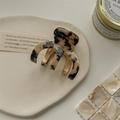 Detail einer Haarklammer aus Acetat mit Schildpattmuster und goldener Feder - Helles Leopardenmuster