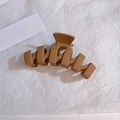 Dettaglio macro di un fermaglio geometrico per capelli marrone moka opaco su carta - Caffè Scuro