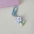 Detail of blue and white flower keychain with light blue D-ring on cream background - Blue