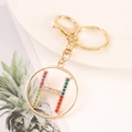 Close-up of golden letter H keychain with colorful rhinestones on white plate - Letter H