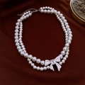 Macro detail of double-layered pearl necklace with crystal bow clasp on velvet - Double Layer Pearl Necklace - Bowknot Style (WN1512)