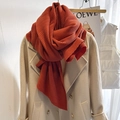 Textured orange pleated scarf for women styled over a beige winter coat collar - Rusty Red