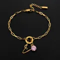 Gouden roestvrijstalen schakelarmband met roze kristal en bedeltje met letter A - Letter V