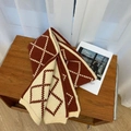Gebreide sjaal met ruitpatroon in dieprood en beige op een houten ondergrond - Rood & Beige Argyle