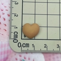 Détail de la taille d'une mini breloque en résine coeur de 1,8 cm sur une règle - Marron