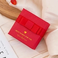 Elegant red textured jewelry gift box featuring a silk ribbon bow and golden text - Red Bow Tie
