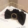Elegant black fabric bow scrunchie featuring a central crystal-encrusted round buckle accent - Solid Black