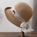 Women's summer straw hat with star ribbon bow shown on a wooden stand for sun protection - Khaki