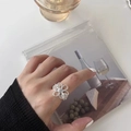 Silver adjustable hollow flower ring with clear zircon stone on a model's hand - Hollow Floral Rhinestone Ring (J4436)