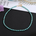 Handmade beaded necklace with turquoise cylinder stones and golden accents on a split background - Style 3
