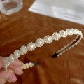 Close-up of elegant white pearl flower headband on delicate metal base with black tips - Flower Pearl Integrated
