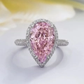 Detailed close-up of a pear-cut pink zircon ring with halo diamond setting and pavé band - US 7 / Pink