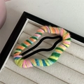 Macro view of colorful knitted wool yarn wrapped around a metal BB hair clip - Mixed Orange Yellow Green