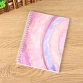 Pink and purple marble textured spiral notebook with gold glitter on wooden desk - A5